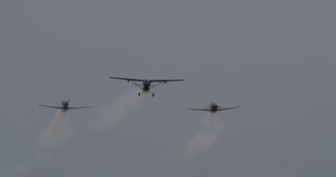 Padova İtalya 22 Haziran 2024: Kasvetli bir günde gri ve bulutlu bir gökyüzüne doğru duman izleriyle sıkı bir şekilde uçan üç hafif uçak. Hava koşullarına rağmen bir koordinasyon ve beceri gösterisi.