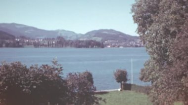 Lucerne, İsviçre 'deki bir otel penceresinden dağların ve Lucerne Gölü' nün huzurlu manzarası. 1950 'lerde çekilen sakin ve klasik bir sahne. Renk 4K arşiv görüntüleri. 