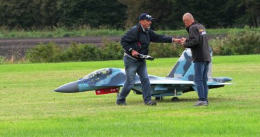 Padua Italy October 6 2024: Realistic RC model of a Sukhoi Su-30 Flanker of the Russian Air Force on a grass airfield as operators adjust its controls. Detailed replica jet.  clipart