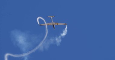 Atina 15 Eylül 2024: Aerobatik planör ters döngü gerçekleştirerek, kıvrımlı duman izlerini açık mavi gökyüzünde fotokopi uzayıyla bıraktı. Swift S-1 L. Bertossio tarafından kullanıldı.. 