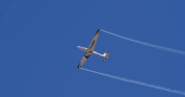 Atina 15 Eylül 2024: Aerobatik planör açık mavi gökyüzünde simetrik duman izleriyle yükseliyor. Hassasiyet, denge, simetri, hareket kavramı. Swift S-1 L. Bertossio tarafından kullanıldı..
