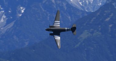 30 Mayıs 2025 Hoher Kasten İsviçre: Douglas DC-3 C-47 Skytrain askeri nakliye uçağı, belirgin çıkartma çizgileri ve 9X gövde işaretli, görkemli İsviçre Alpleri üzerinde uçar.