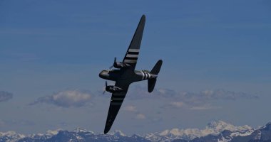 30 Mayıs 2025 Hoher Kasten İsviçre: Douglas DC-3 C-47 Skytrain askeri nakliye uçağı, D-Day istila çizgilerine sahip, görkemli İsviçre Alpleri üzerinde dinamik bir uçuş gerçekleştirir..