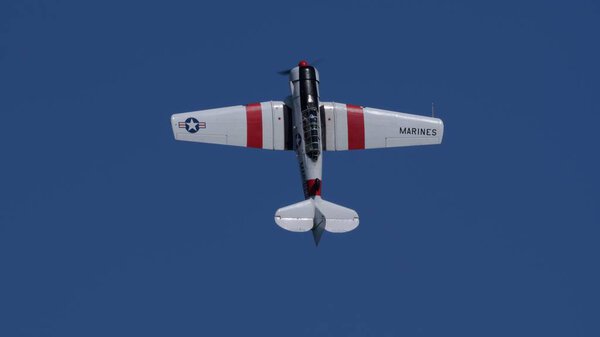 JUNE 29, 2025: Padua, Italy: A perfectly symmetrical underside view of a historic North American T-6 Texan with US Navy markings, flying against a clear, deep blue sky.