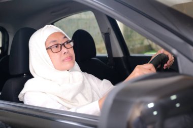 Beyaz Müslüman kıyafetleriyle Endonezyalı kadın sürücü.