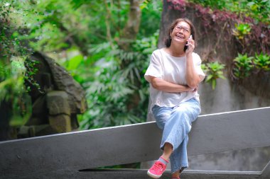 Bahçede tek başına oturan bir kadın özel telefon görüşmesi yapıyor.