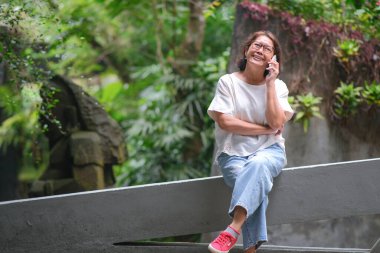 Bahçede tek başına oturan bir kadın özel telefon görüşmesi yapıyor.