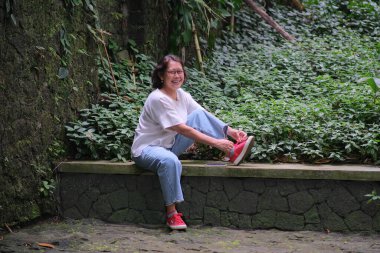 Kadın parkta yürüdükten sonra oturup dinleniyor.