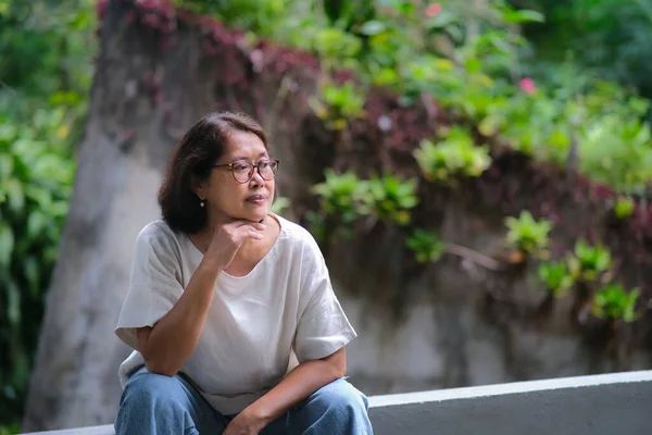 stock image Asian woman sitting alone and taking a rest after a long walk in the park