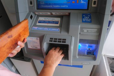 Deri cüzdan tutan eller, Yogyakarta 'daki ATM' den para çekme, 5 Şubat 2023
