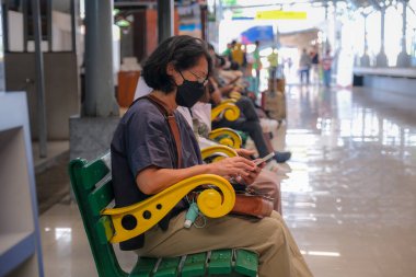 Yogyakarta 'da tren istasyonunda oturan bir kadın 5 Şubat 2023' te bekleme salonunda bekliyor.