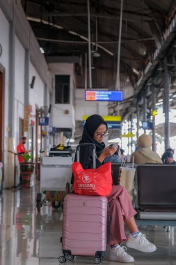 15 Şubat 2023 'te Yogyakarta tren istasyonunda bavullu bir kadın oturuyor.