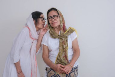 İki yetişkin Asyalı kadın Ramazan tatilinde bir araya gelip, dedikodu yapıyor ve şakalarını paylaşıyor.