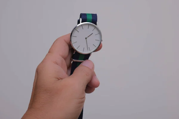 Hand showing an old model of wrist watch over plain background