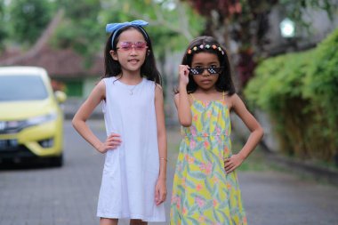 Oyuncak güneş gözlükleriyle poz veren iki küçük Asyalı kız.