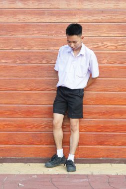 Beyaz tişörtlü genç bir adamın portresi ve ahşap arka planda kot pantolon.