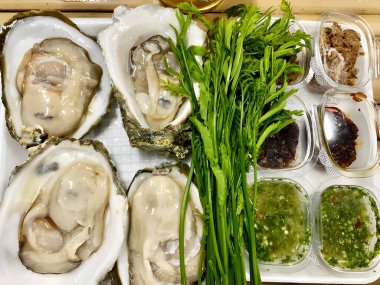 Beyaz kasede taze çiğ istiridye ve akasya yaprağı.