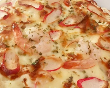 Jambonlu pizza, mozzarella, soğan ve peynir beyaz tabakta.