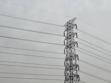 Yüksek voltaj kulesi, bulutlu gökyüzünde güç iletim hatları.