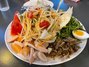 Lezzetli Asya yemekleri ve papaya salatasının yakın görüntüsü.