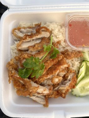 Ahşap arka planda köpük kutusunda pilavlı kızarmış tavuk.