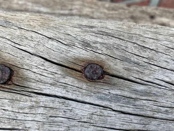 old weathered rusty nails on a rusty wood surface.