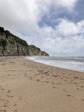 Denizin ve kayalıkların olduğu bir sahilin dikey görüntüsü.