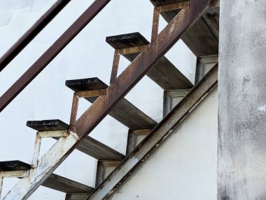 Beyaz duvarda eski paslı demir merdiven