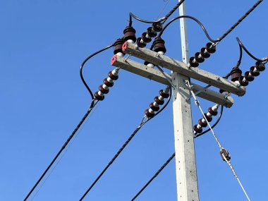 Mavi gökyüzünün arka planında yüksek voltaj kabloları olan yüksek enerji hatları.