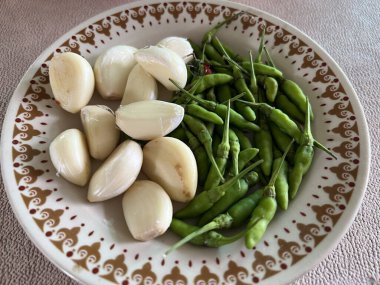 Masada bir tabak yeşil biber ve sarımsak.