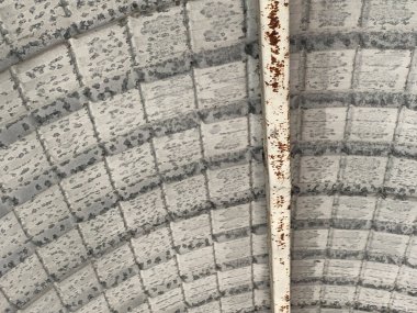 Gri metal örgülü beyaz bir boyayla kaplı gri duvar.