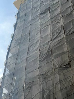 Mavi gökyüzünün altındaki bir binanın ön cephesinde iskele.