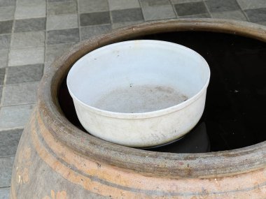 Beyaz bir su tankında eski siyah plastik bir kase.