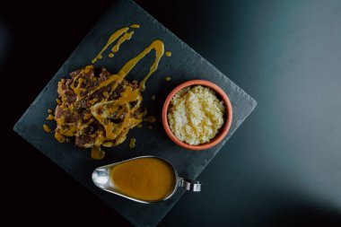 Veal osso buco with sauce presented on a slate plate accompanied by white rice and a metal sauce dish. Foodie. close-up. selective focus. aerial view