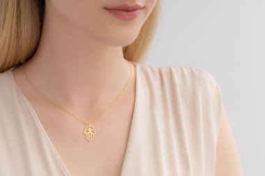 Krem rengi bluz giymiş bakımlı bir bayanın boynunda zarif gümüş bir kolye var. E-ticaret, sosyal medya, ürün satışları için fotoğraflar.