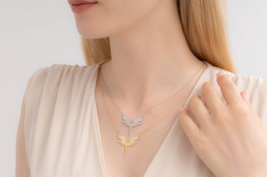 Krem rengi bluz giymiş bakımlı bir bayanın boynunda zarif gümüş bir kolye var. E-ticaret, sosyal medya, ürün satışları için fotoğraflar.