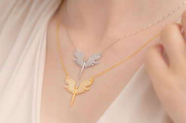 Krem rengi bluz giymiş bakımlı bir bayanın boynunda zarif gümüş bir kolye var. E-ticaret, sosyal medya, ürün satışları için fotoğraflar.