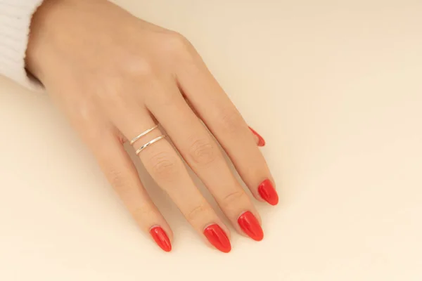 Jewelry on the hand of the girl with red nail polish. Extraordinary Women jewelry concept. Jewelry image for e-commerce, online sale, social media.