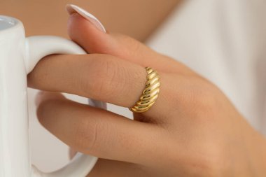 Güzel ojeli, bakımlı bir kadın ellerinde altın bir yüzük gösteriyor. Kadın mücevher konseptiyle ürün imajı.