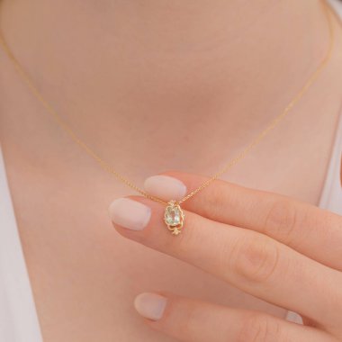 Açık tenli bir bayanın üzerinde klasik tasarımı olan zarif elmas bir kolye. Zincirli küçük altın bir kolye..