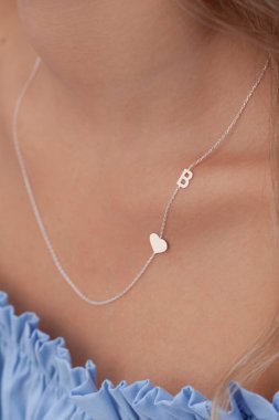 Bakımlı bayan renkli elbisesiyle özel mücevherlerini sergiliyor. E-ticaret satışları için modellenmiş mücevher fotoğrafı.