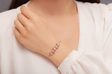 Beyaz elbiseli bayan zarif mücevherler gösteriyor. Kadın mücevher konseptiyle ürün imajı. Bilezik, kolye, küpe, yüzük..