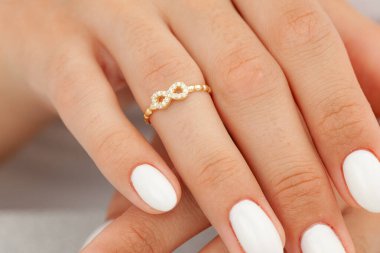 İyi bakımlı tırnakları ve mücevher konsepti olan bir imaj. Kadın model parmağında altın zarif bir yüzük gösteriyor. E-ticaret, sosyal medya ve tüm platformlar için mücevher fotoğrafçılığı.