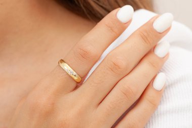 İyi bakımlı tırnakları ve mücevher konsepti olan bir imaj. Kadın model parmağında altın zarif bir yüzük gösteriyor. E-ticaret, sosyal medya ve tüm platformlar için mücevher fotoğrafçılığı.