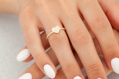 İyi bakımlı tırnakları ve mücevher konsepti olan bir imaj. Kadın model parmağında altın zarif bir yüzük gösteriyor. E-ticaret, sosyal medya ve tüm platformlar için mücevher fotoğrafçılığı.