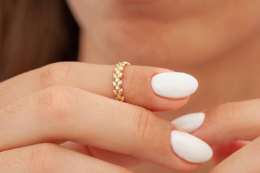 İyi bakımlı tırnakları ve mücevher konsepti olan bir imaj. Kadın model parmağında altın zarif bir yüzük gösteriyor. E-ticaret, sosyal medya ve tüm platformlar için mücevher fotoğrafçılığı.