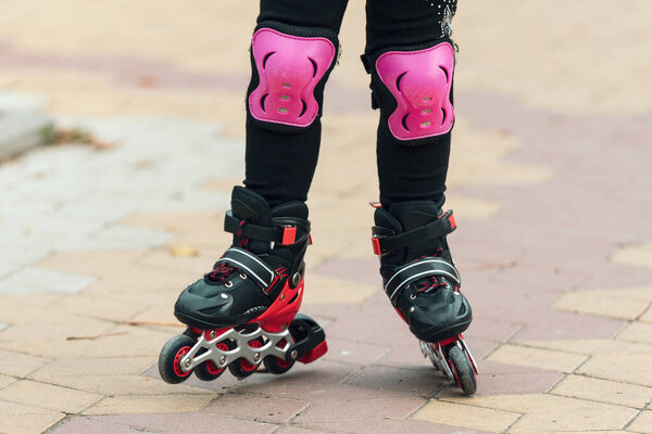 Legs of a child rollerblading in the park.