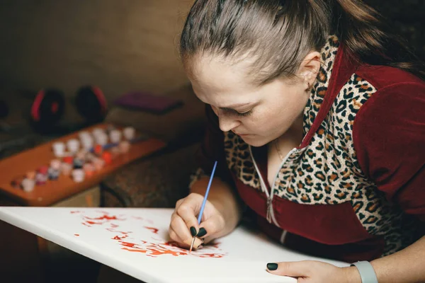 Girl paints a picture by numbers with paints.