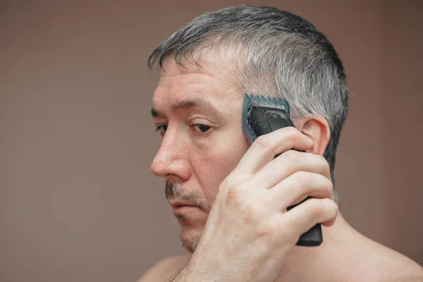 stock image Man cutting his own hair with a clipper.