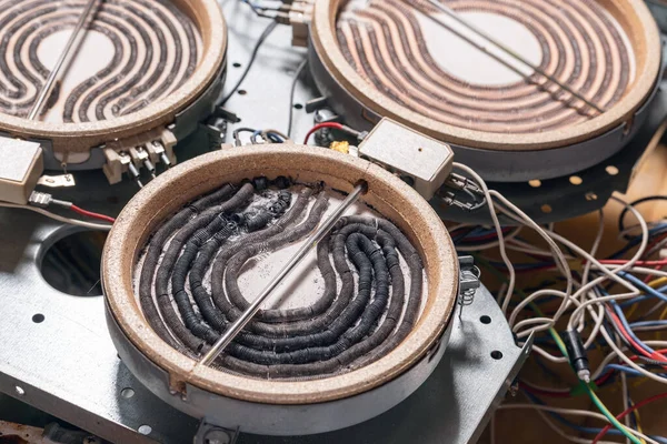 stock image Disassembled electric burner with burned out heating elements, wires and cables.